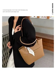Detail of khaki leather tote bag with silk scarf on handle and front pocket