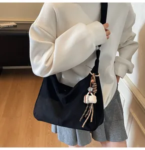 Detail van de zwarte canvas draagtas met koffiehangertje gedragen door een model in casual stijl