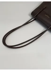 Detail of dark brown lychee grain leather bag with gold fashion lettering and bead straps
