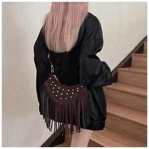 Detail of dark brown suede crossbody bag featuring gold studs and long tassel fringe