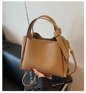 Detail view of brown pebble grain leather bucket bag with top handles and adjustable strap