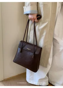Close-up of dark brown lychee leather bag with wooden bead detail on the strap