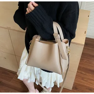 Detail of beige lychee leather bucket bag featuring knot handle and golden metal buckle