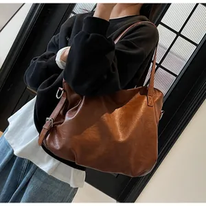 Detail of adjustable shoulder strap with silver buckle on brown leather tote bag