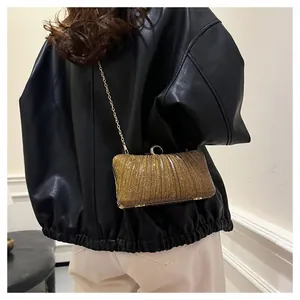 Détail de la pochette de soirée à paillettes dorées avec texture plissée et chaîne