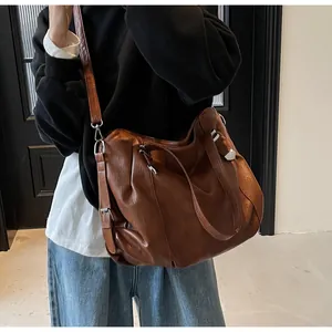 Detail of dark brown oversized tote bag with soft faux leather texture and adjustable strap