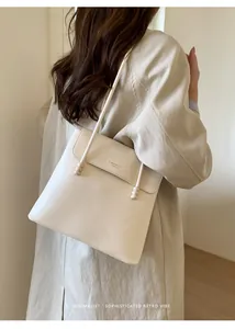 Detailed view of cream tote bag with litchi grain leather and ball buckle strap