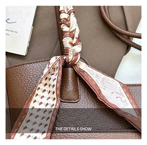 Close-up of brown lychee leather tote handle wrapped in a decorative floral silk ribbon