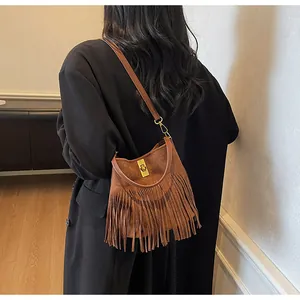 Detail of brown suede bucket bag featuring layered long tassels and a metallic lock