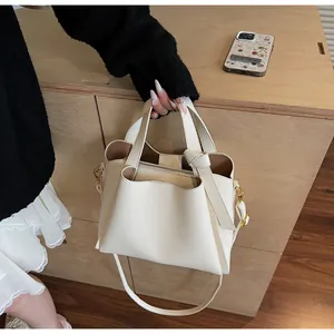 Detail view of white lychee leather bucket bag featuring unique knotted handles and metal strap buckle