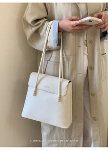 Detail of minimalist cream leather bucket bag with beaded strap and fashion logo