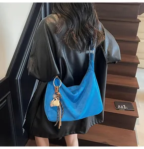 Blauwe suède hobo schoudertas met koffiekopje hanger over een zwart leren jasje