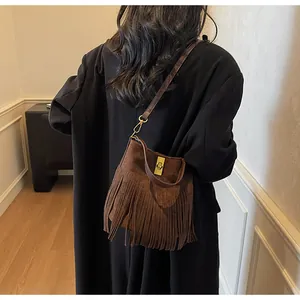 Détail du sac seau en daim marron foncé avec de longues franges et un fermoir doré