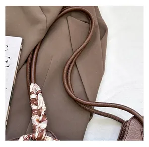 Detail shot of brown lychee grain leather tote bag featuring a decorative silk scarf on strap