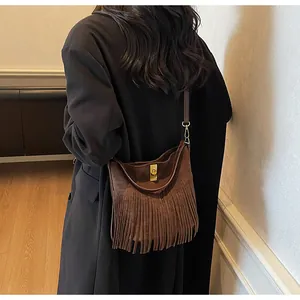 Détail d'un sac seau en daim marron avec de longues franges et un fermoir doré