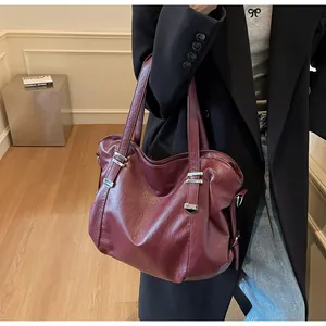 Close-up of vintage burgundy faux leather tote bag with silver metal rivets and texture