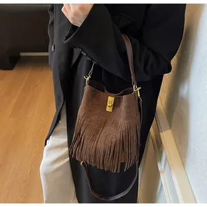 Détail d'un sac seau en daim marron avec des franges et une boucle en métal doré