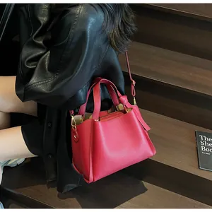 Detail of red pebbled leather bucket bag with gold hardware on a dark wooden background