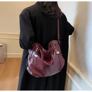 Close-up of a large burgundy faux leather tote bag with silver rivets and dual straps