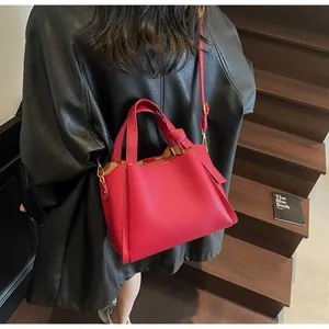 Detail of red lychee grain leather bucket bag featuring unique knotted handle and side pleats