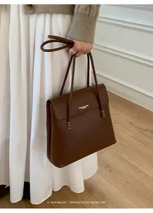 Detail of retro brown leather bucket bag with gold lettering and beaded handle accents