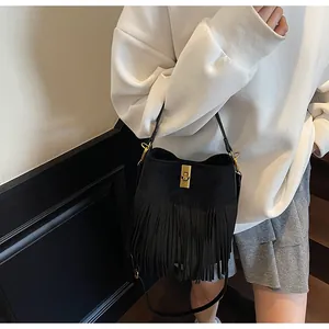 Vue détaillée du sac seau noir en daim à franges avec fermoir rotatif en métal doré