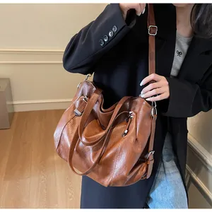 Detail view of large brown retro leather tote bag with silver studs and adjustable strap