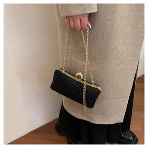 Détail de la pochette de soirée noire avec plis verticaux et fermoir en anneau serti de diamants