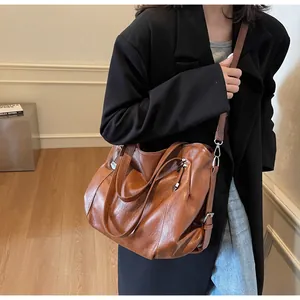 Detail of dark brown vintage leather tote bag showing silver zippers and shoulder strap
