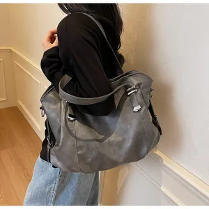 Close-up of grey vintage soft leather tote bag with silver hardware on a model's shoulder