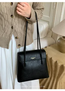 Detail of black lychee leather shoulder bag with gold logo and sphere bead shoulder strap