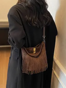 Sac seau minimaliste en daim marron foncé avec franges porté en bandoulière tendance