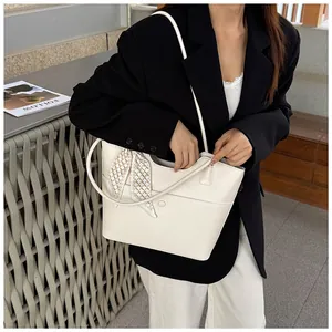Detail of white lychee leather tote bag with elegant patterned silk scarf on strap
