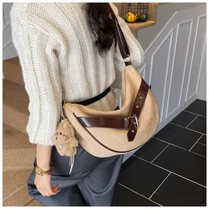 Detail van beige suède tas met bruine leren riemen en een schattige pluche beer hanger