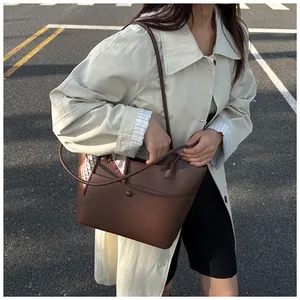Brown leather tote bag with checkered scarf detail shown in outdoor street style shot