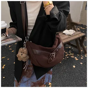 Detail van de suède crossbodytas met lederen riemen en een pluchen hondenhangertje