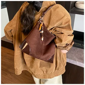 Detalle de bolso hobo de ante marrón con ribete de charol y adorno de cuentas