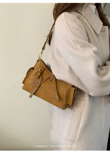 Detail of a brown suede shoulder bag with side pocket and elegant metal buckle