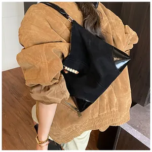 Detalle del bolso tote de ante con esquinas de cuero reforzado y colgante de madera