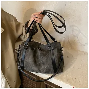 Detail view of large charcoal canvas crossbody bag with black leather handles and zipper