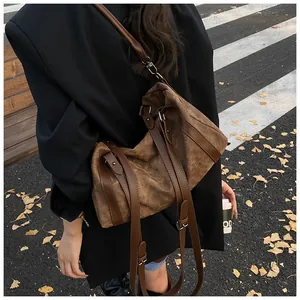 Detail of vintage brown canvas crossbody bag with leather trim on model in autumn street