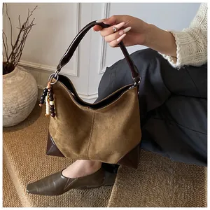 Detalle del bolso tote de retazos de ante y cuero con un amuleto decorativo de cuentas
