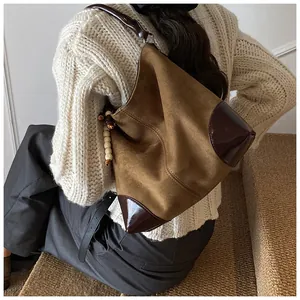 Detalle de bolso hobo de ante con adornos de cuero y colgante de cuentas en el modelo