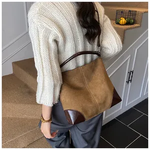 Detalle de bolso tote grande de ante marrón con refuerzos de cuero en una modelo