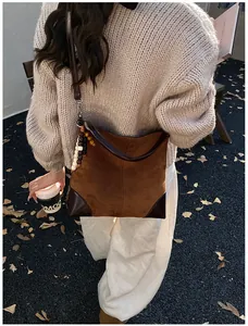 Detalle del bolso tote de ante con esquinas de cuero y accesorio de amuleto de cuentas