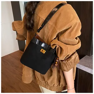 Detail van zwarte matte suède emmer tas met goudkleurig slot en houten kralen kwastje
