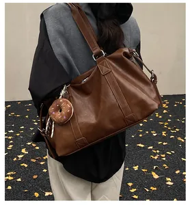 Detail of dark brown leather travel tote bag with donut pendant and silver buckle