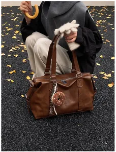 Close-up of retro brown large leather travel bag with a cute donut plush charm