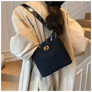 Detail van zwarte crossbody emmerstas met mat suède en glanzende laklederen afwerkingen