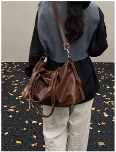 Brown vintage faux leather travel bag shown on shoulder in an outdoor setting